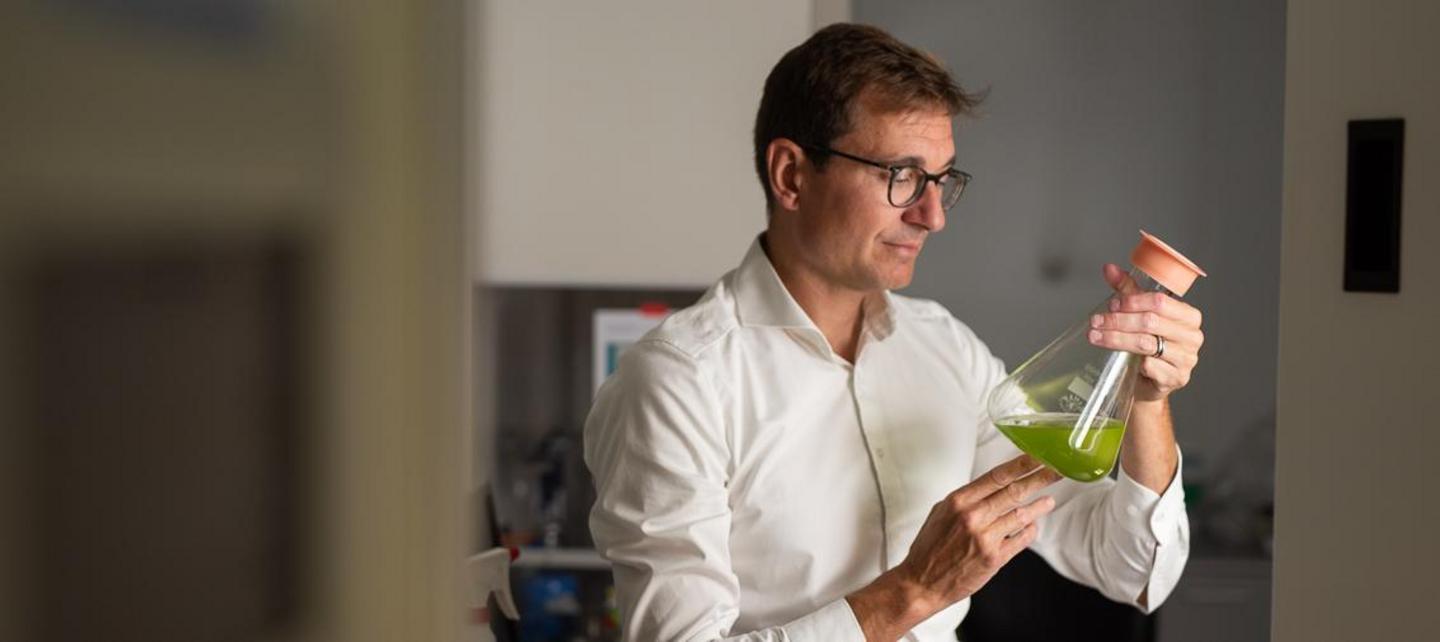 Mann mit Erlenmeyerkolben, darin grüner Inhalt