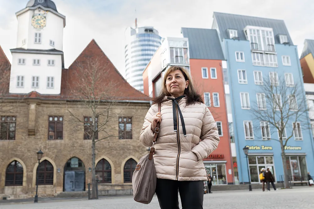 Frau auf einem Platz, im Hintergrund Gebäude