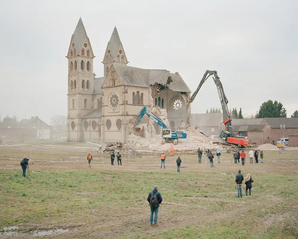 Ein Bagger zerstört eine Kirche.
