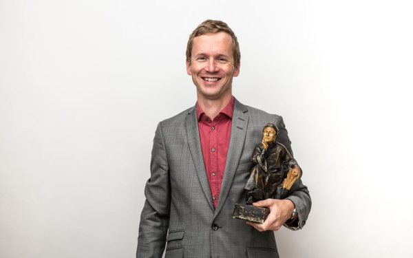 Portrait eines Mannes mit mittelalterlicher Holzstatue in der Hand