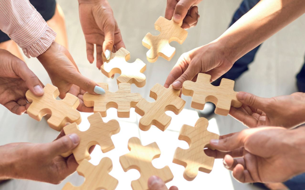 viele Hände mit Holzpuzzleteilen