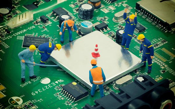 Das Bild zeigt winzige Bauarbeiterfiguren, die an einem Computerchip arbeiten.