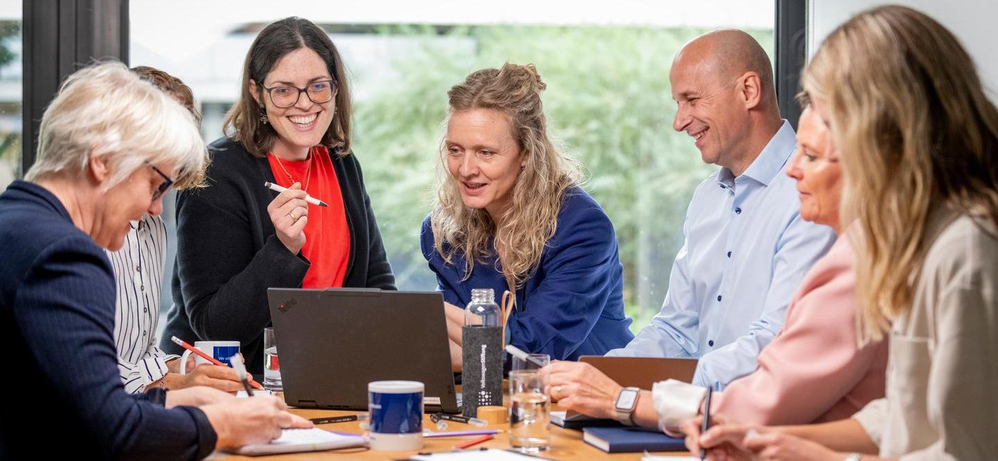 Mehrere Personen in einer Arbeitssituation mit Laptop