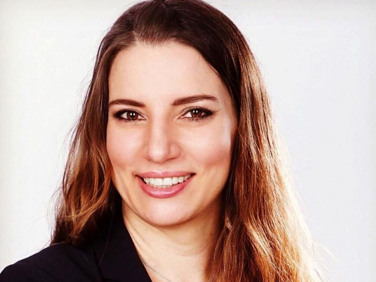 Das Bild zeigt eine lächelnde Frau, die in die Kamera schaut.