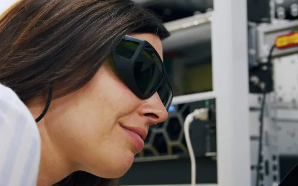 Frau mit getönter Laborbrille schaut Technik an