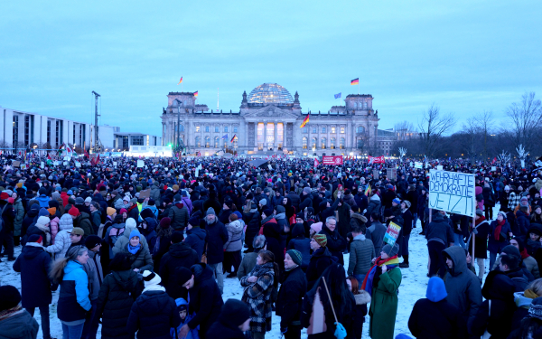 Demonstrierende vor dem Berliner Reichstagsgebäude sind zu sehen sowie ein Plakat mit der Aufschrift "Wehrhafte Demokratie jetzt".