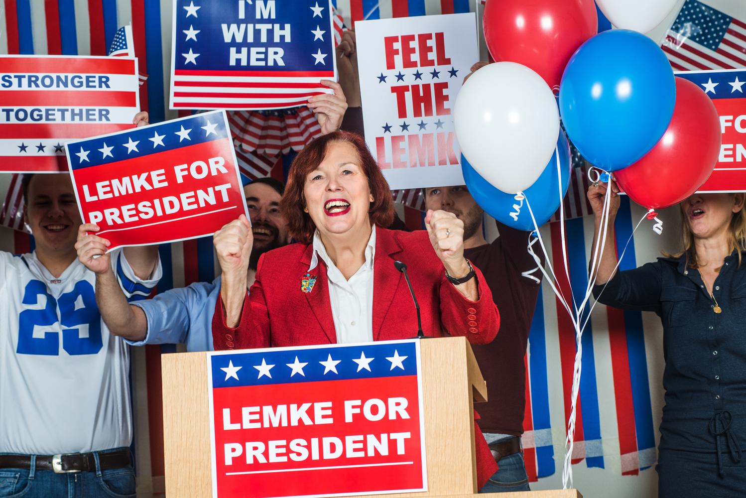 eine Frau am Rednerpult, dahinter Menschen mit Plakaten mit Aufdruck "Lemke for President"