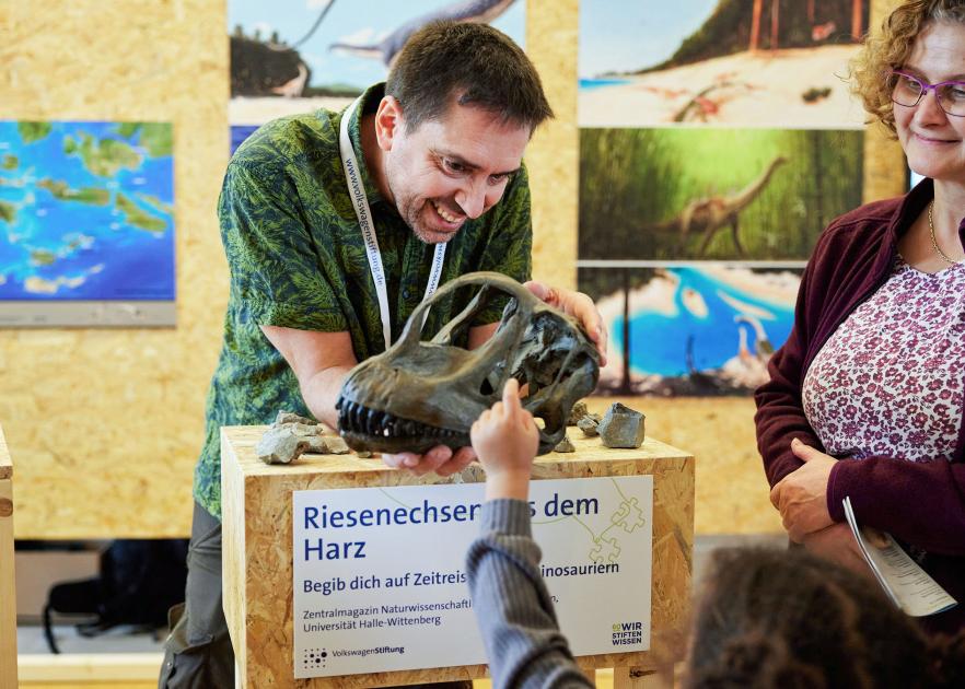 Dr. Oliver Wings zeigt einen Dinosaurierschädel.