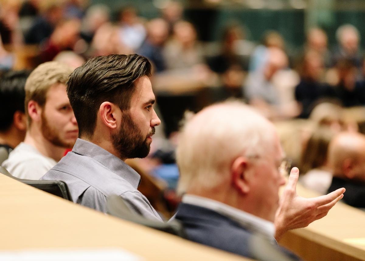 Mann im Publikum in einem Auditorium stellt eine Frage