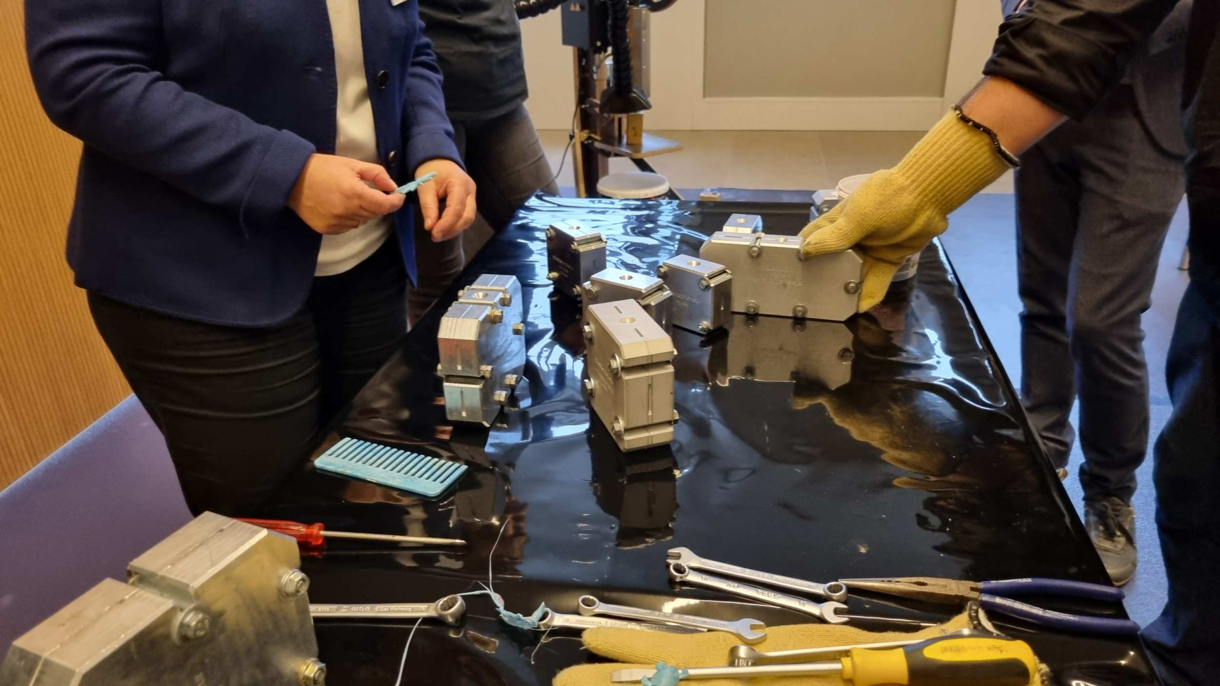 Verschiedene Hände hantieren an Gussformen auf einem Tisch