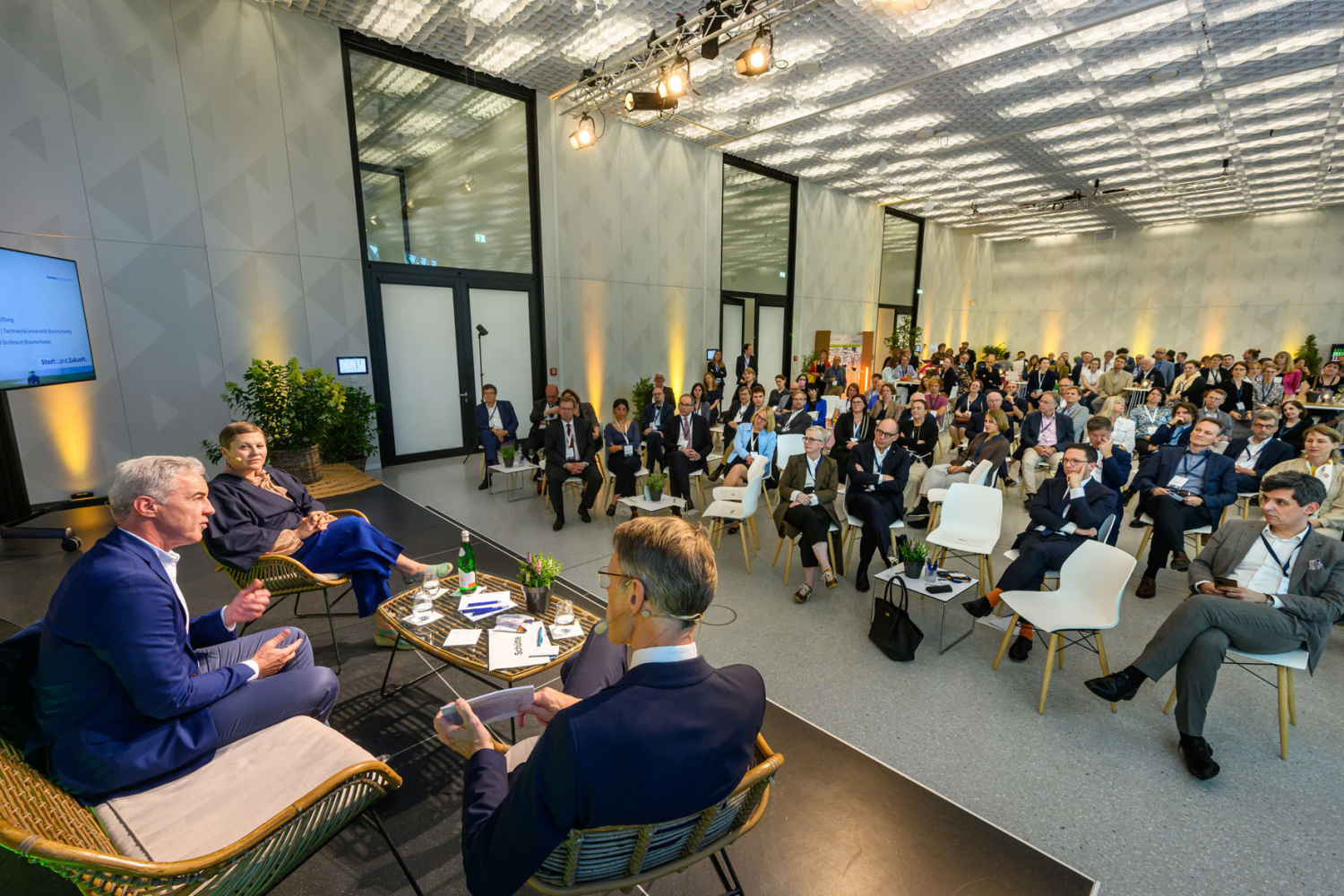 Blick von oben auf Podiumsgäste und Publikum