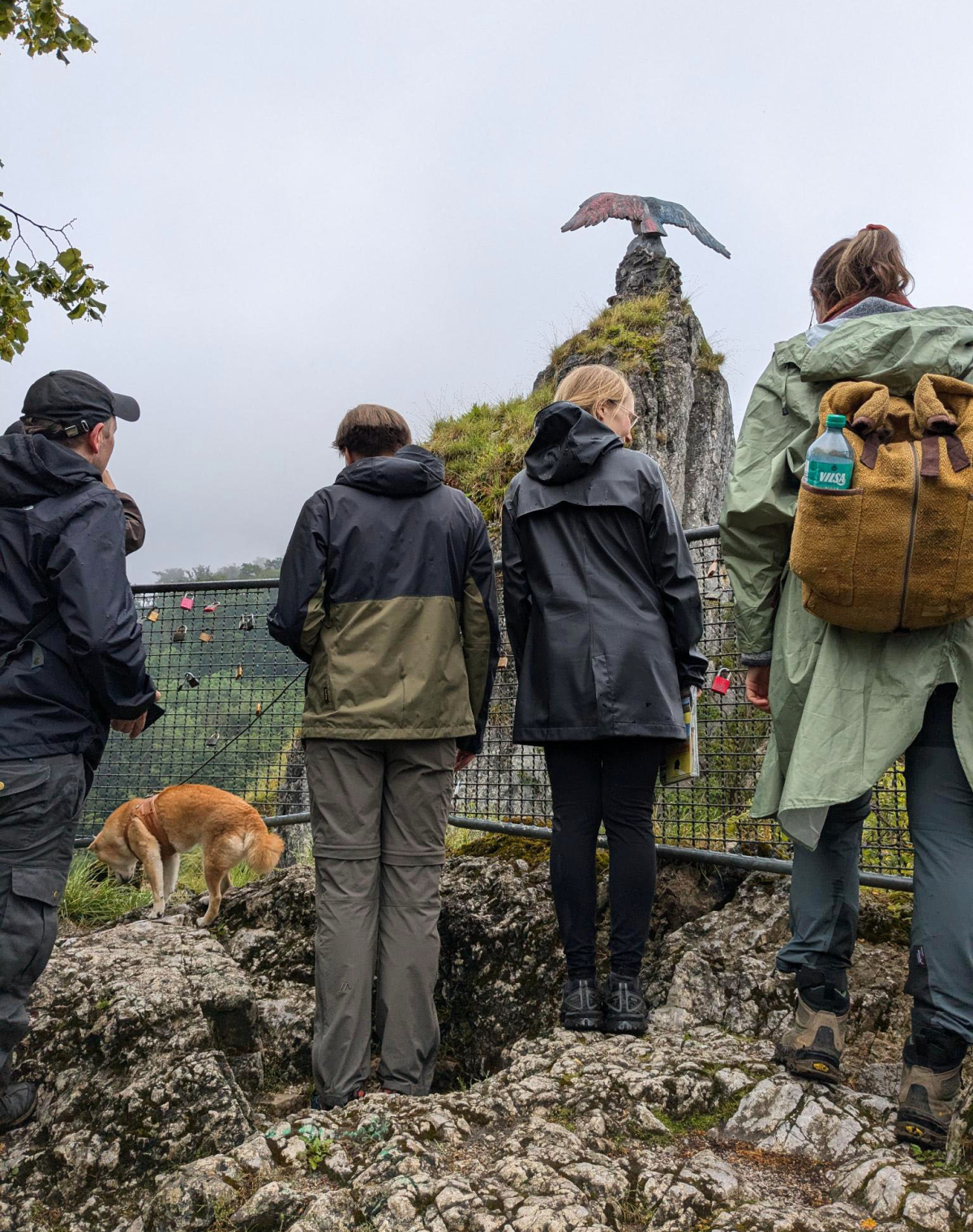 Mehrere Personen bei einer Wanderung blicken auf ein Denkmal mit einem Adler