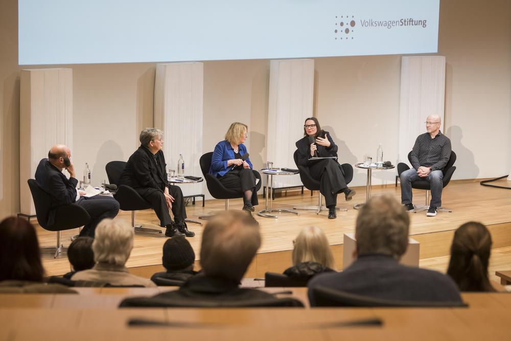 Eine Gruppe von fünf Menschen sitzt auf einer Bühne und diskutiert.
