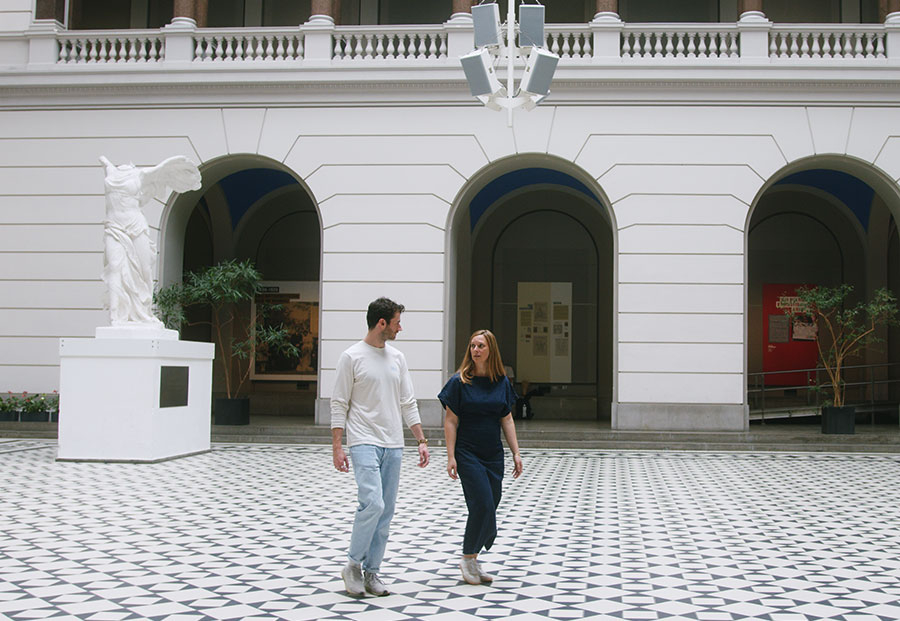 Ein Mann und eine Frau laufen durch einen lichtdurchfluteten Innenhof