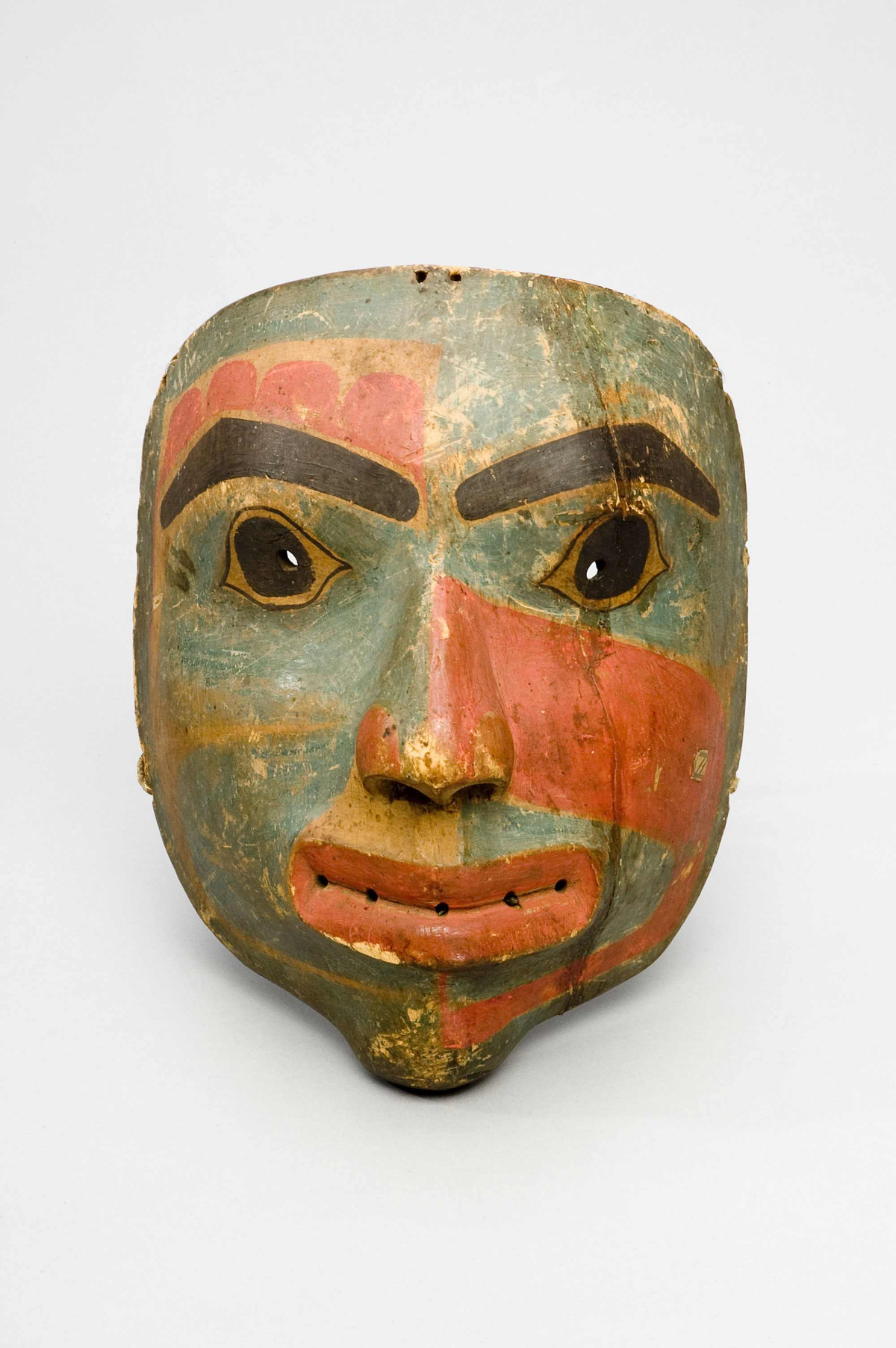 grün-rote Holzmmaske eines Gesichts