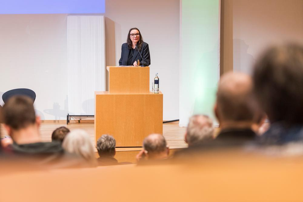 Eine Frau hält einen Vortrag auf einer Bühne.