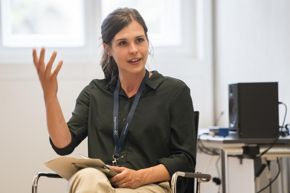 Eine junge Wissenschaftlerin spricht auf einem Podium.