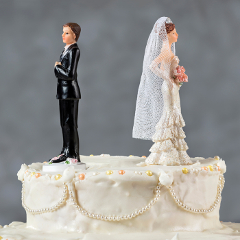 Zu sehen ist eine Hochzeitstoprte mit Dekofiguren Braut und Bräutigam, die sich den Rücken zuwenden. 
