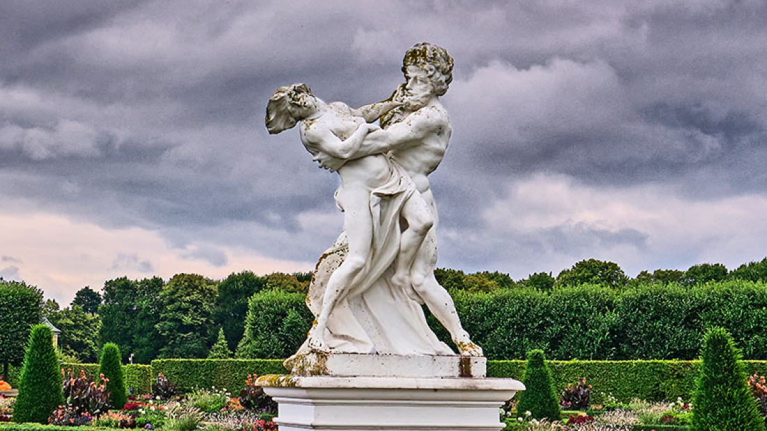 Das Bild zeigt eine Sandsteinplastik im großen Garten in Herrenhausen vor einem wolkenbehangenen Himmel