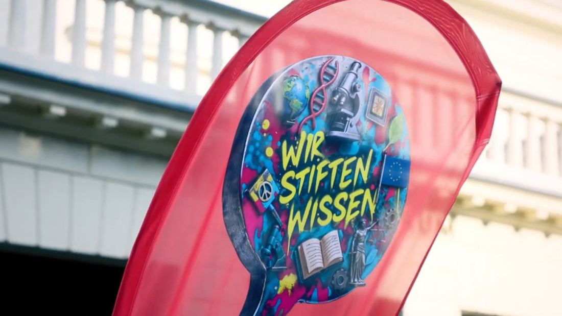 Fahne mit Schriftzug "Wir stiften Wissen" vor einer herrschaftlichen Fassade
